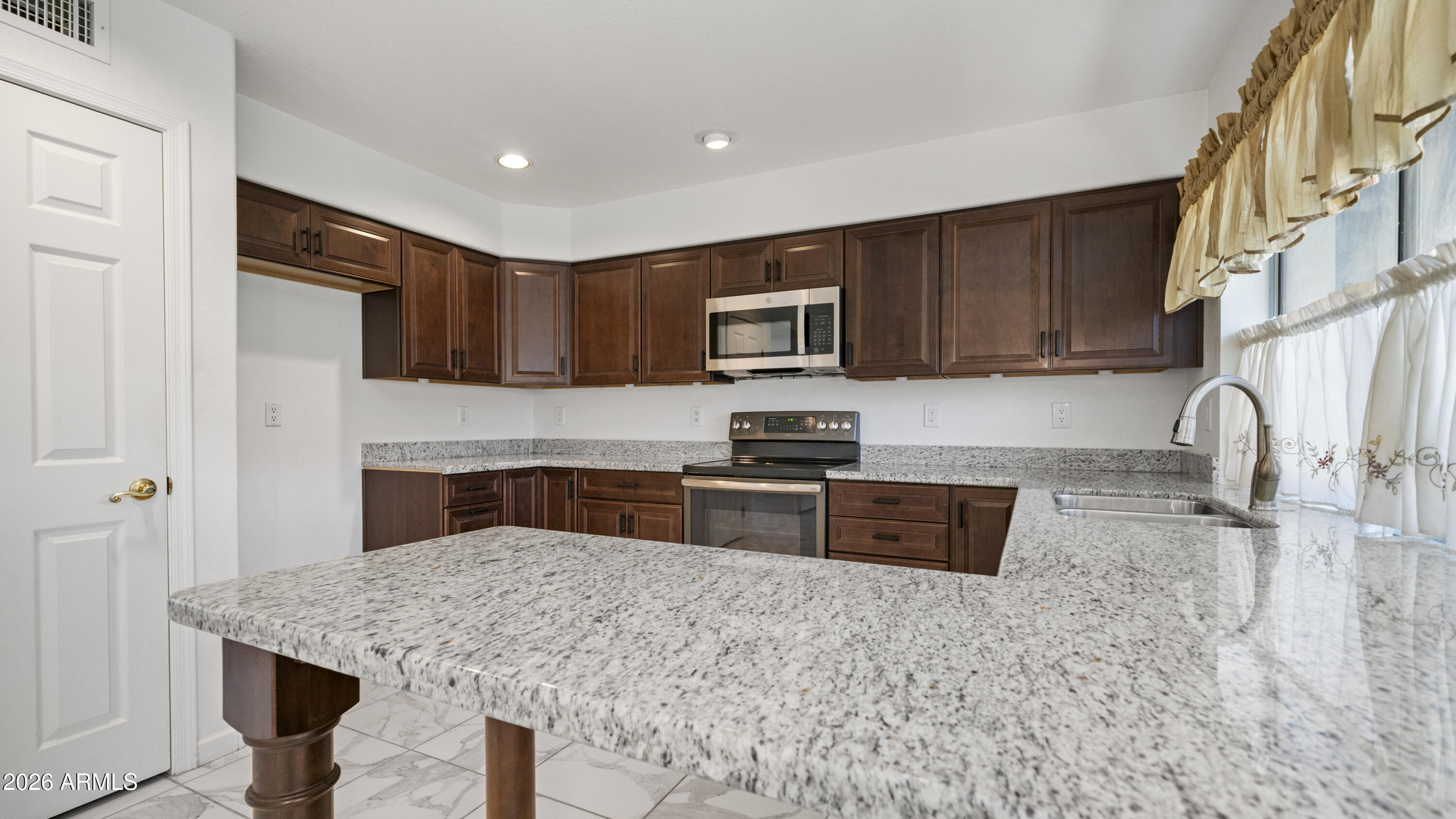 6620 West Redfield Road Glendale, AZ 85306 - Photo 6 of 33 a kitchen with granite countertop a stove sink and microwave