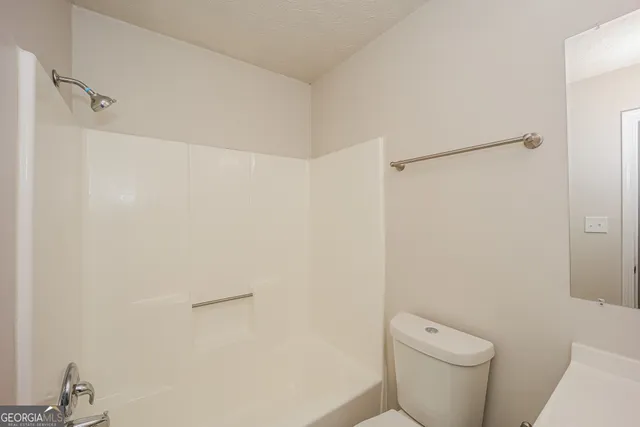 a white toilet sitting next to a shower