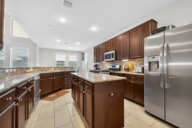 a kitchen with stainless steel appliances granite countertop a stove top oven a sink refrigerator and cabinets