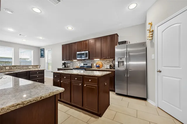 a kitchen with stainless steel appliances granite countertop a refrigerator a sink a stove a microwave and island