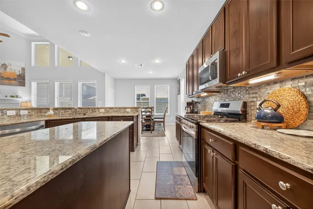 a large kitchen with stainless steel appliances granite countertop a lot of counter space and a sink