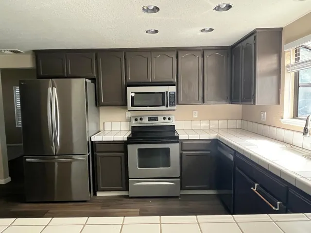 a view of a livingroom with a fireplace a ceiling fan and wooden floor