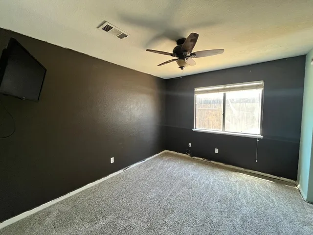 an empty room with window and a ceiling fan