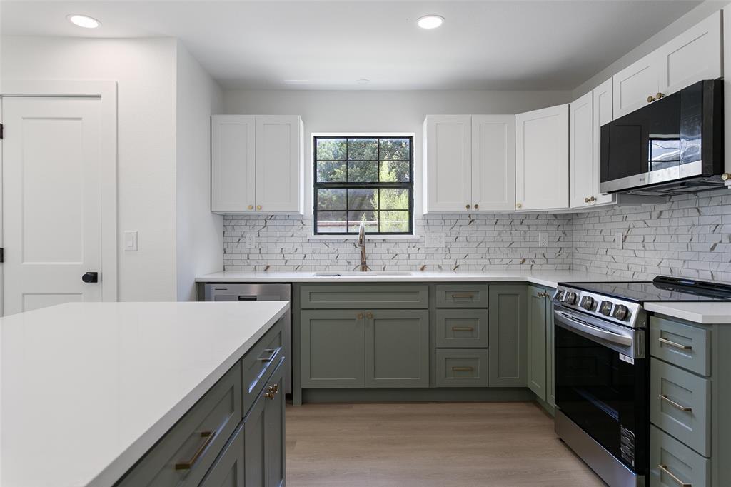 1346 South Reno Road Springtown, TX 76082 - Photo 4 of 24 Kitchen featuring two-tone cabinetry with white upper cabinets and sage green lower cabinets, white stone countertops, and a full tile backsplash