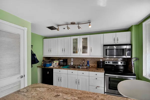 a kitchen with white cabinets a sink and stainless steel appliances