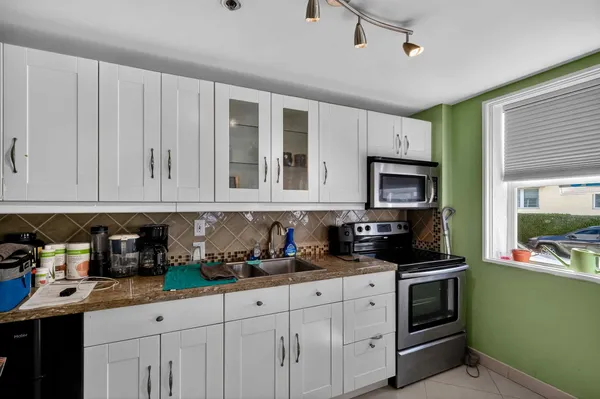 a kitchen with a sink a counter cabinets and living room view