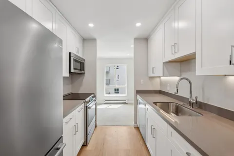 a kitchen with stainless steel appliances granite countertop a sink a stove and a refrigerator