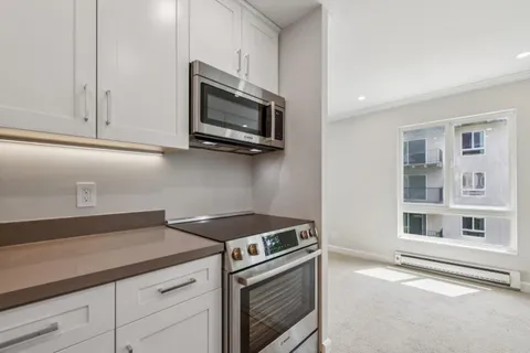 a kitchen with stainless steel appliances white cabinets and a stove top oven