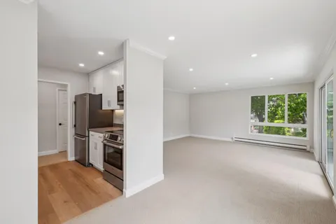 an empty room with stainless steel appliances kitchen island granite countertop a refrigerator and a stove top oven