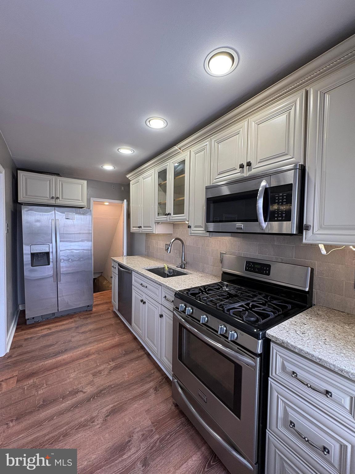 210 Wabash Avenue Lansdowne, PA 19050 - Photo 5 of 12 a kitchen with stainless steel appliances granite countertop a stove a sink dishwasher a microwave oven and a refrigerator with wooden cabinets