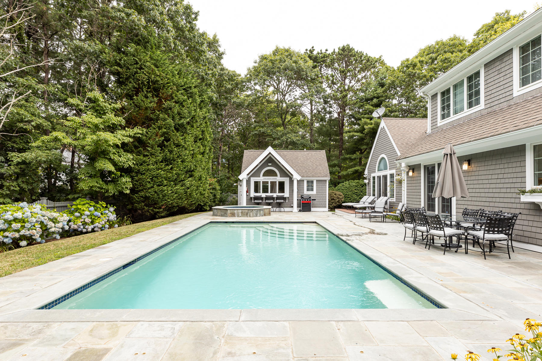 36 Topping Lift Mashpee, MA 02649 - Photo 3 of 38 a white house with a large pool and lawn chairs under an umbrella