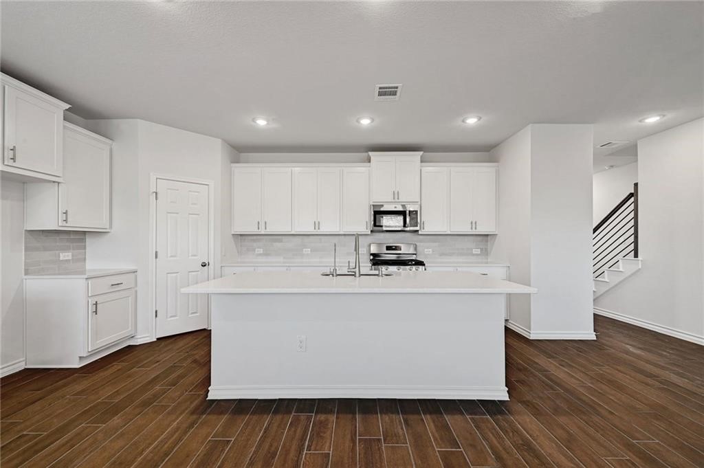 806 Pepperbark Loop Buda, TX 78610 - Photo 9 of 39 a kitchen with stainless steel appliances granite countertop a white stove top oven and white cabinets