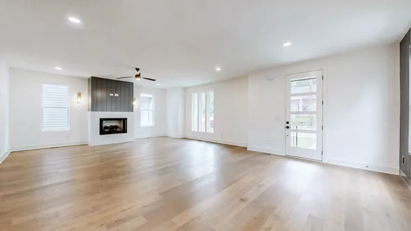 an empty room with wooden floor fireplace and windows