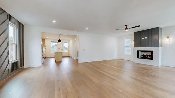 a view of an empty room with wooden floor and a fireplace