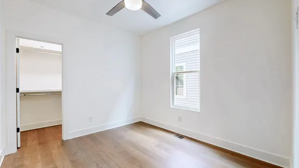 an empty room with wooden floor and windows