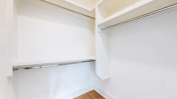 an empty room with closet and a chandelier fan