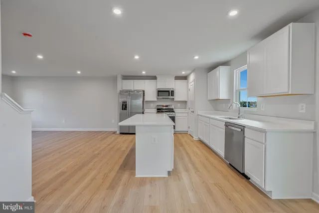 a large kitchen with a large counter top a sink stainless steel appliances and cabinets