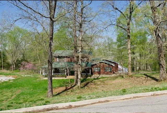 a house is sitting in middle of the green field