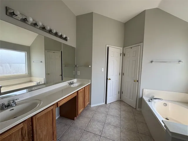 a spacious bathroom with a bathtub sink and mirror
