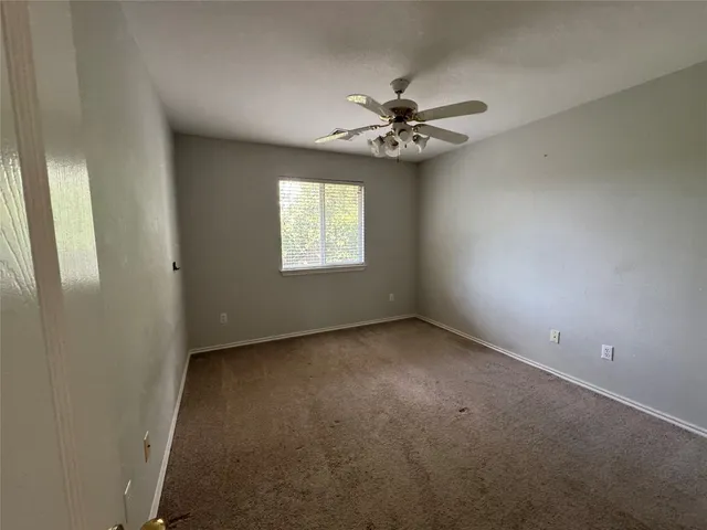 an empty room with a window and a fan