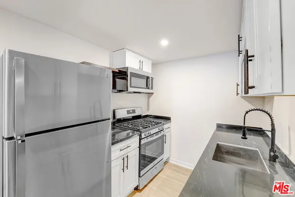 a kitchen with stainless steel appliances granite countertop a sink stove and refrigerator