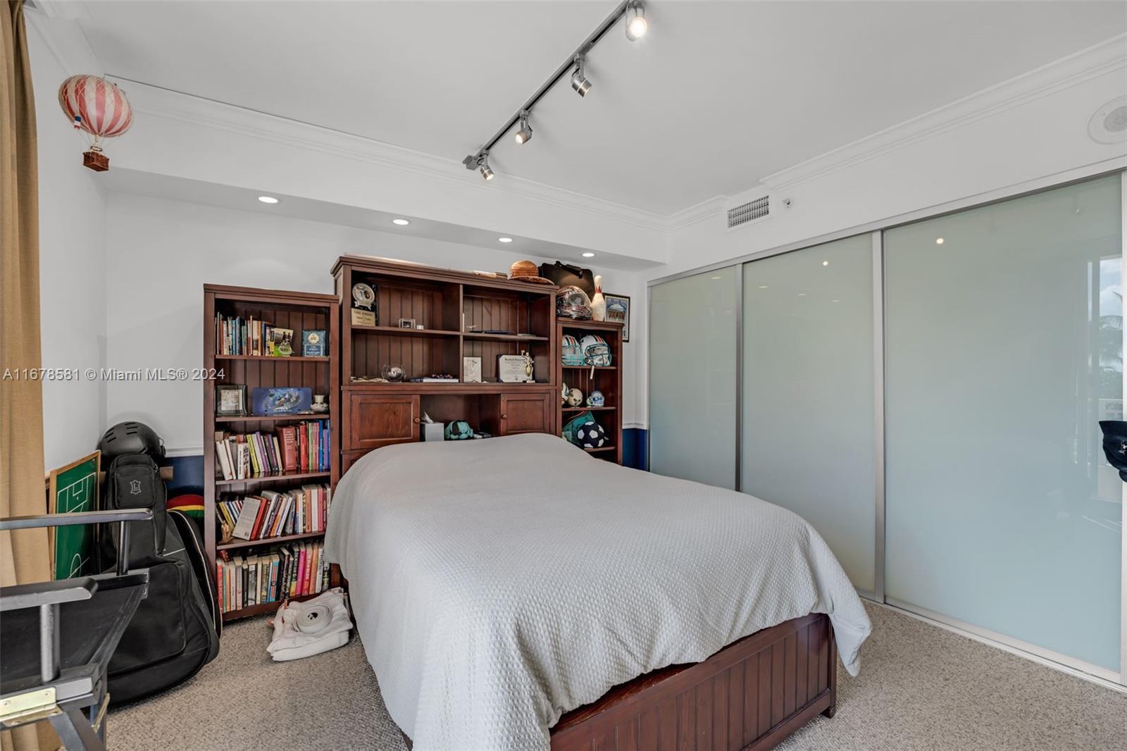 765 Crandon Boulevard, Unit 305 Key Biscayne, FL 33149 - Photo 39 of 55 a bed room with a bed and a book shelf