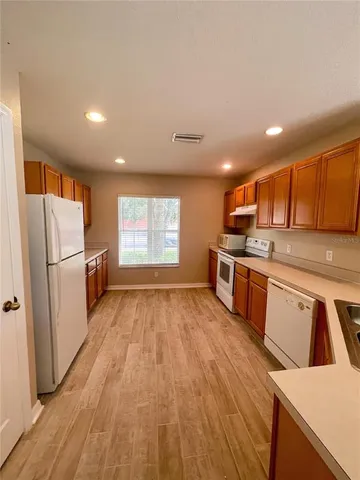 a kitchen with stainless steel appliances granite countertop a refrigerator a stove and a wooden floors