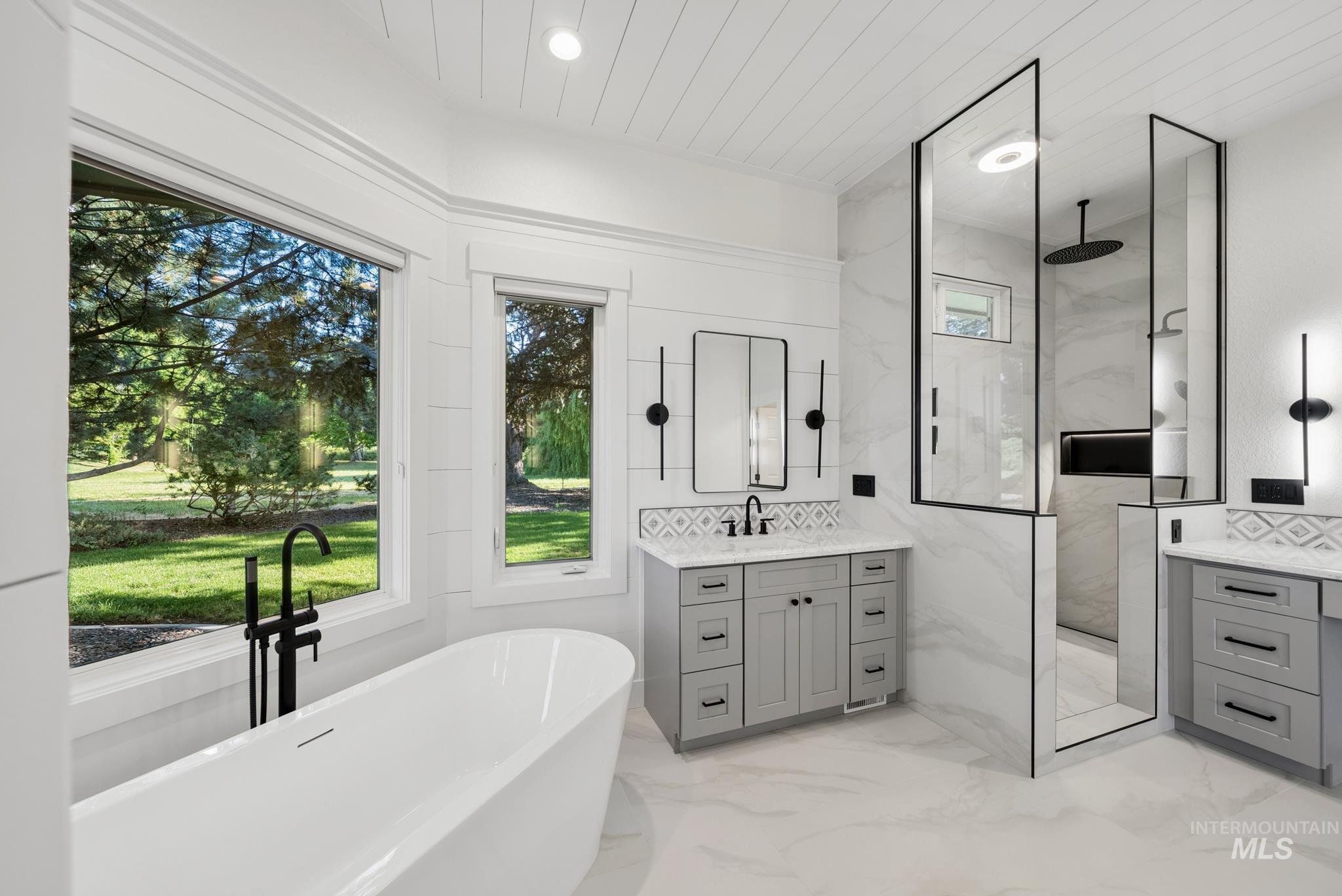 2050 Artesian Road Eagle, ID 83616 - Photo 27 of 49 Freestanding soaking tub set against a backdrop of multiple windows, complemented by white shiplap walls and a dual-sink vanity with gray cabinetry