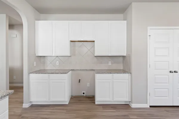 a kitchen with stainless steel appliances granite countertop a white cabinets and a wooden floor