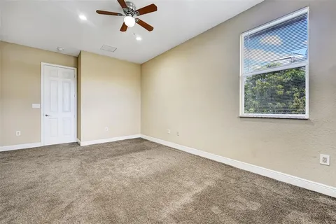 a view of an empty room with a ceiling fan and window
