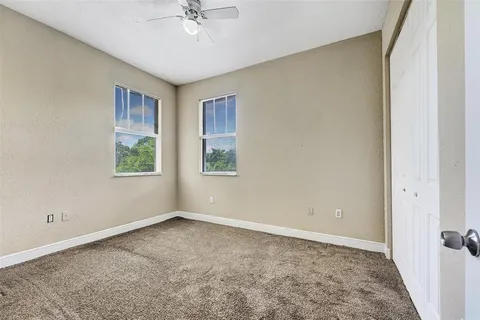 an empty room with windows and fan