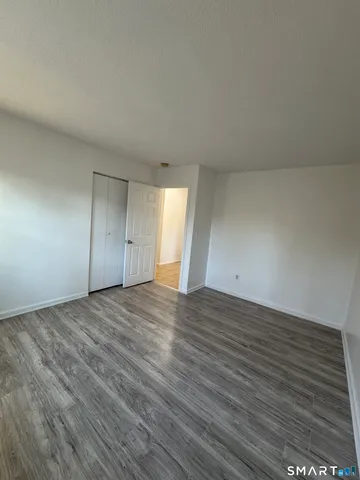 a view of an empty room with wooden floor and window