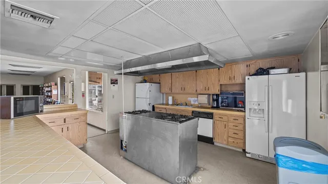 a kitchen with stainless steel appliances a stove a refrigerator a sink a dining table and chairs with wooden floor