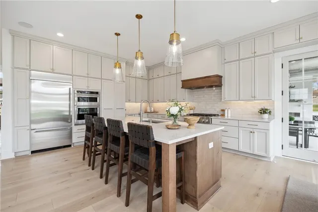 a kitchen with kitchen island granite countertop a sink a counter space stainless steel appliances and cabinets