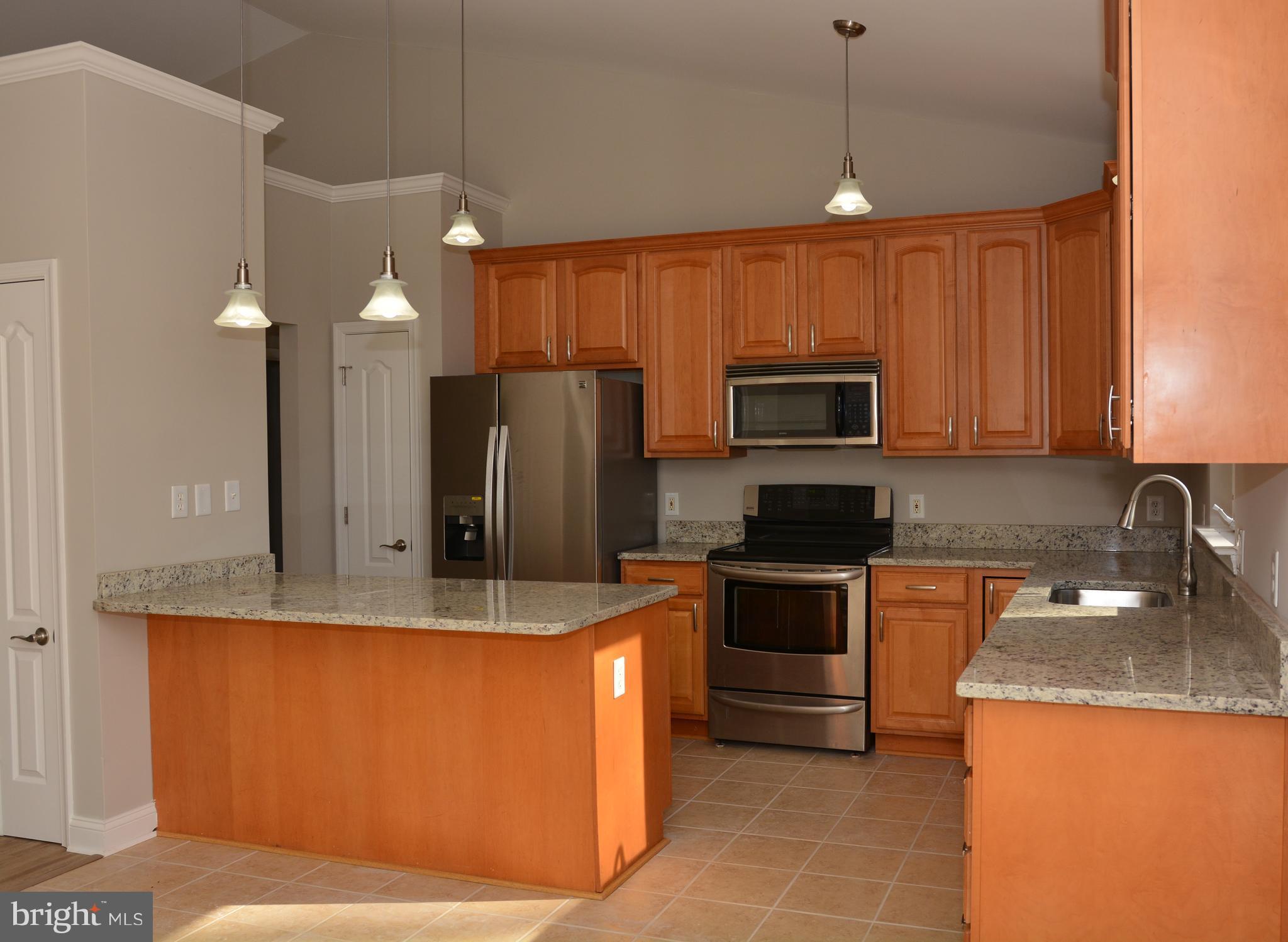 11231 Rawhide Road Lusby, MD 20657 - Photo 7 of 18 a kitchen with granite countertop a stove top oven a sink dishwasher a refrigerator and a microwave oven
