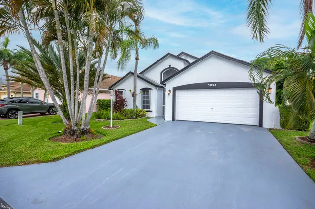 a front view of a house with a garden and trees