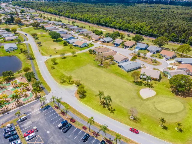 view of a swimming pool with lawn chairs and plants