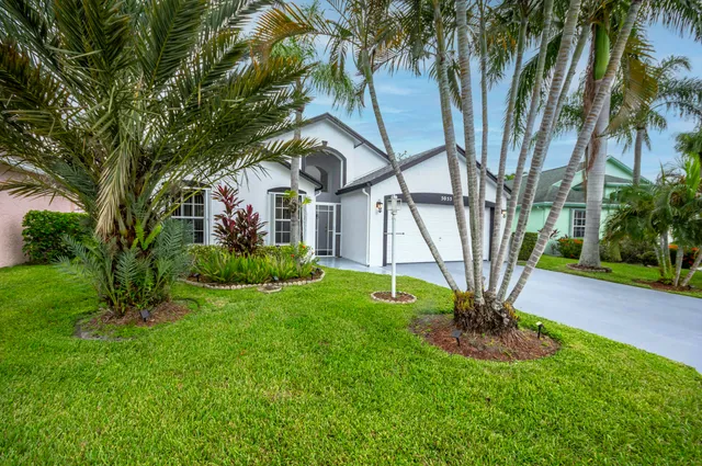 a view of a house with a yard and palm trees