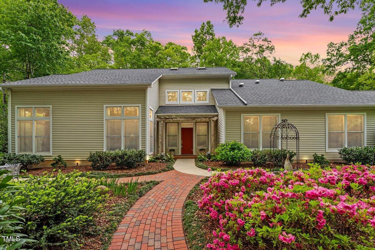 a front view of a house with lots of flowers around
