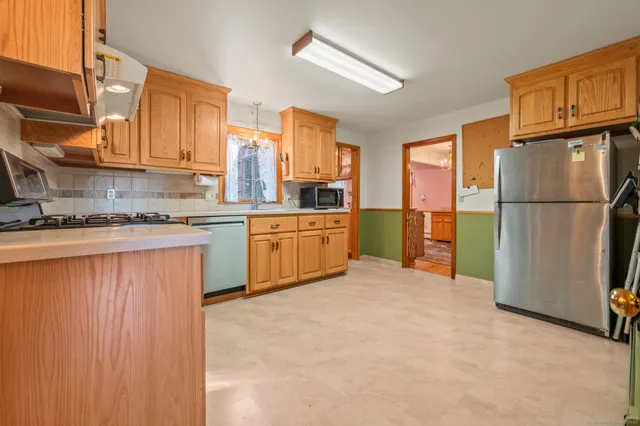 a kitchen with stainless steel appliances granite countertop a refrigerator a stove and a sink