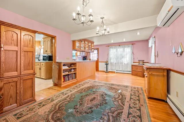 a large kitchen with stainless steel appliances granite countertop a refrigerator a oven a dining table and chairs with wooden floor