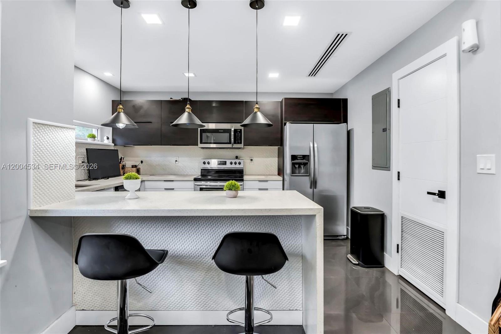 1741 Northwest 44th Street Miami, FL 33142 - Photo 12 of 45 a kitchen with stainless steel appliances a dining table chairs and a refrigerator