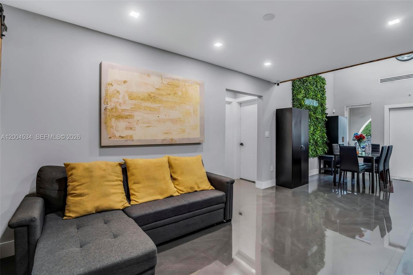 1741 Northwest 44th Street Miami, FL 33142 - Photo 5 of 45 a hallway with a couch and potted plant with wooden floor