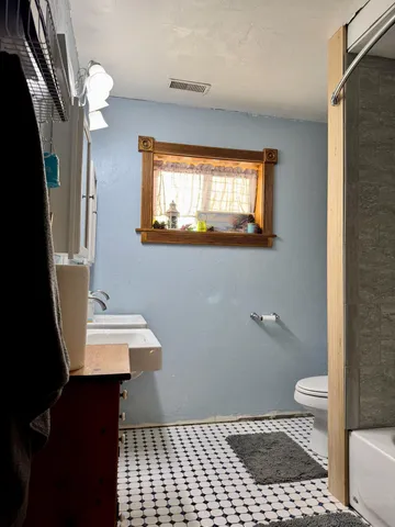 a bathroom with a sink a toilet a window and vanity
