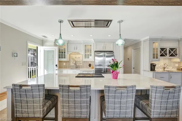 a kitchen with stainless steel appliances kitchen island granite countertop a dining table chairs sink and cabinets
