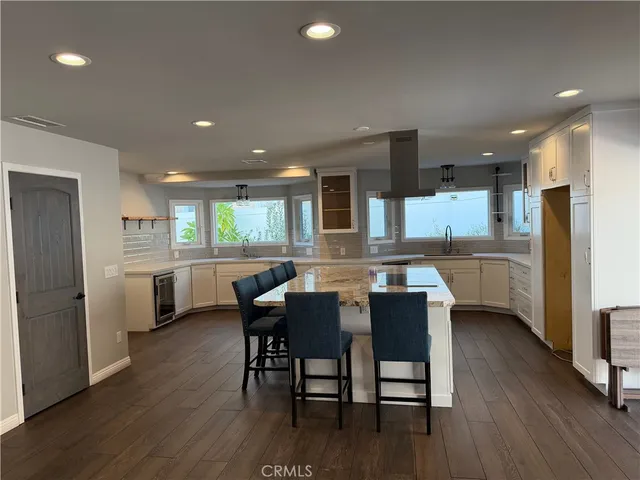 a kitchen with a dining table chairs refrigerator wooden floor and cabinets