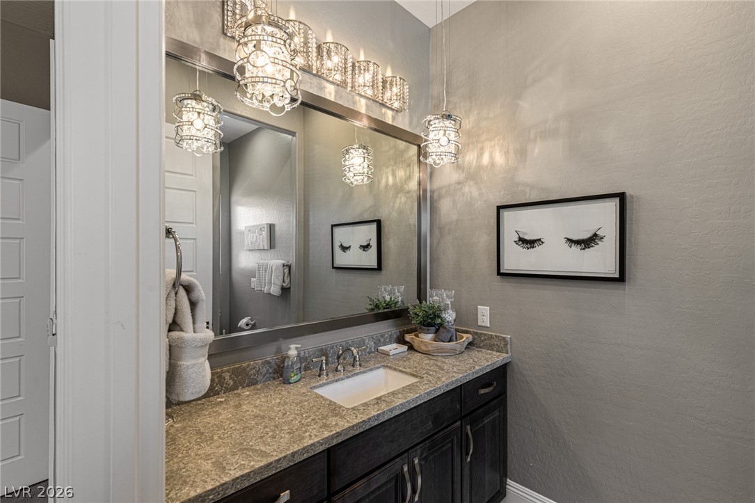 10118 Copper Edge Road Las Vegas, NV 89148 - Photo 26 of 48 Granite counters and crystal lighting fixtures elevate this well-appointed bathroom vanity.