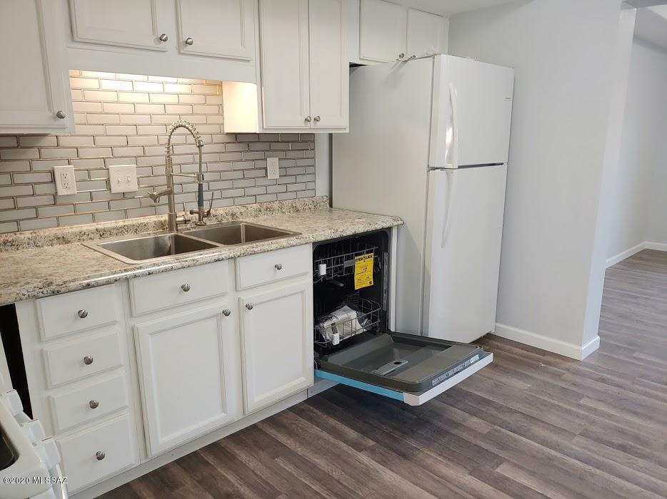 1454 West Roger Road Tucson, AZ 85705 - Photo 5 of 20 a kitchen with stainless steel appliances granite countertop a refrigerator sink and white cabinets