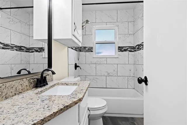 a bathroom with a granite countertop sink a toilet and bathtub