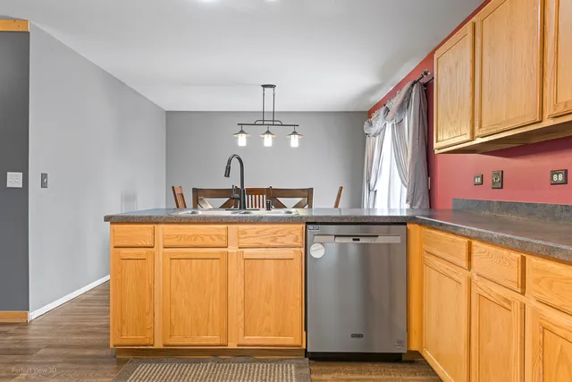 a kitchen with stainless steel appliances granite countertop a refrigerator a sink dishwasher and wooden cabinets with wooden floor